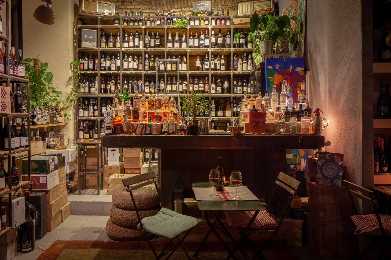 Interno dell’Enoteca Il Covino a Roma: scaffali di bottiglie e tavolino con due calici di vino rosso